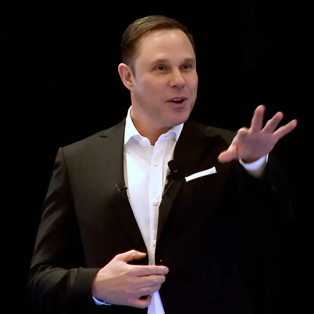 Magician & Mentalist, Randy Charach wearing black coat and performing on stage