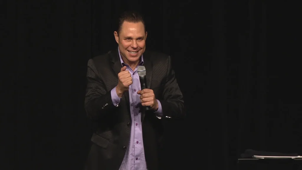 Randy Charach with holding mic and speaking.
