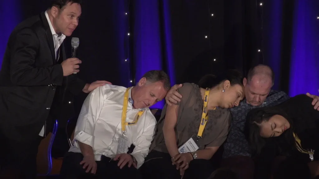 Audience members experiencing a hypnotic performance.