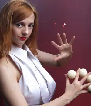Magical Katrina, holding four small balls, between her fingers.