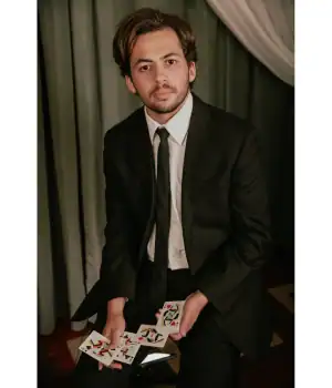 Paul Robaia Magic wearing black coat and holding cards.