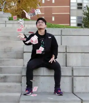 Travis Kim, throwing cards in the air as part of a magic act.